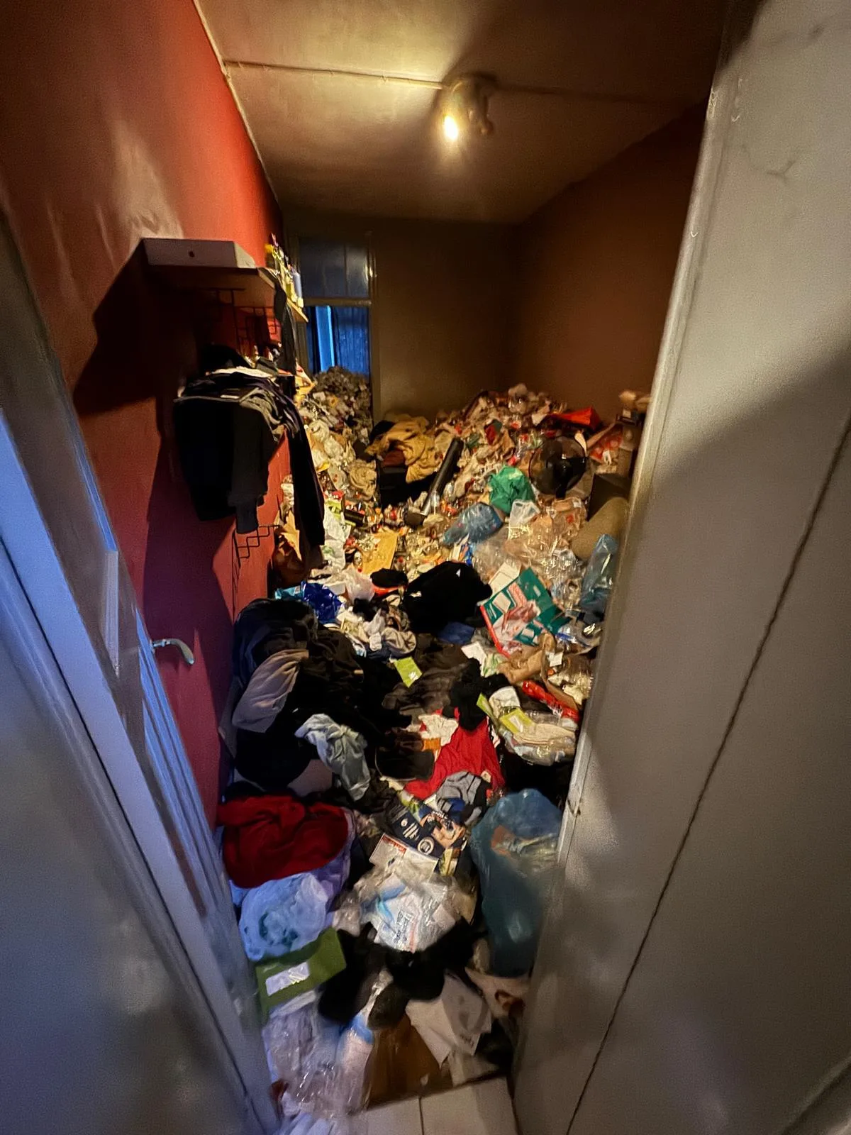 Avant débarras à Genappe — Chambre saturée de vêtements et cartons, vidée